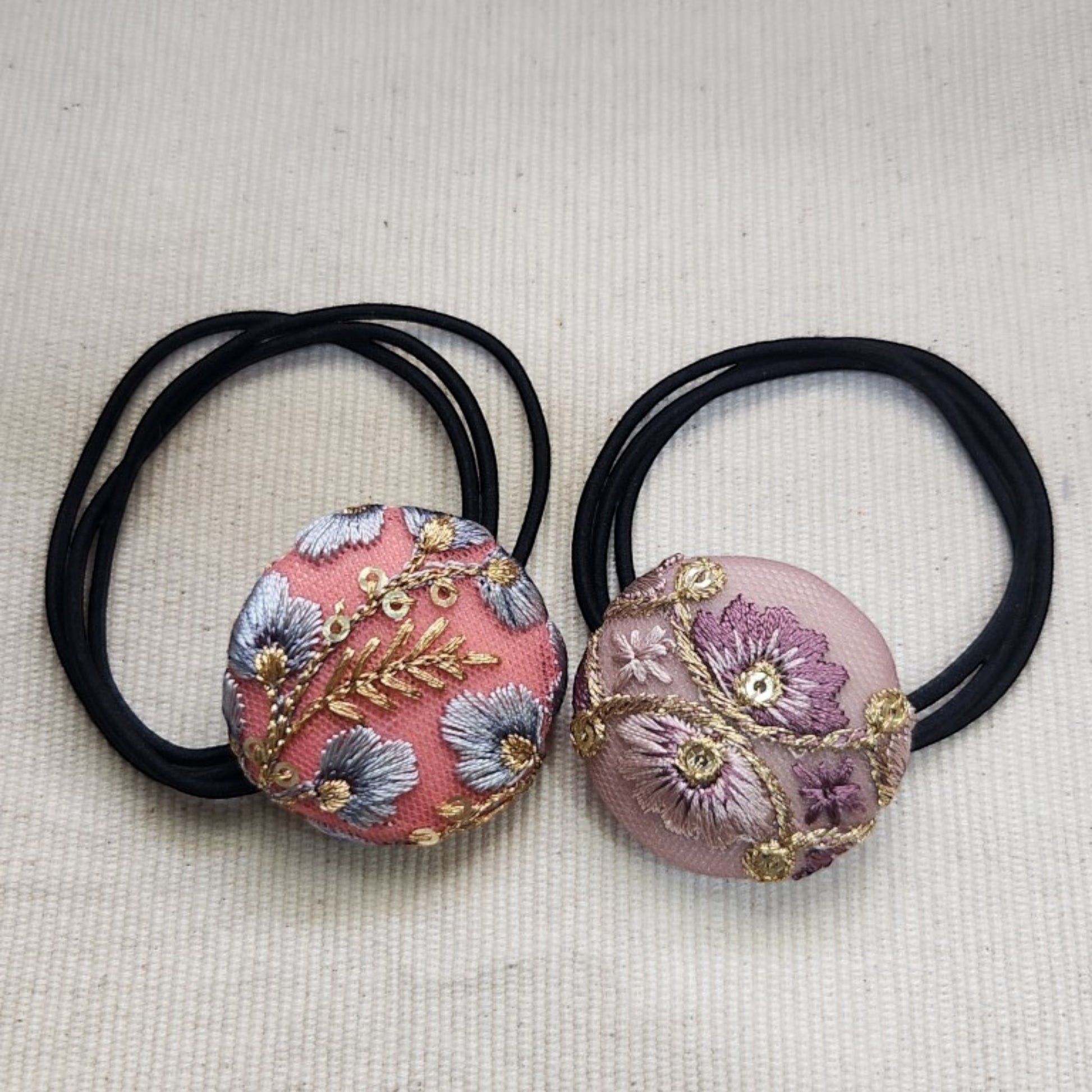 Angelica Handmade 兩款圓形髮圈，採用印度刺繡緞帶製成，分別為粉色與淡紫色花卉刺繡圖案，搭配黑色彈性髮圈。